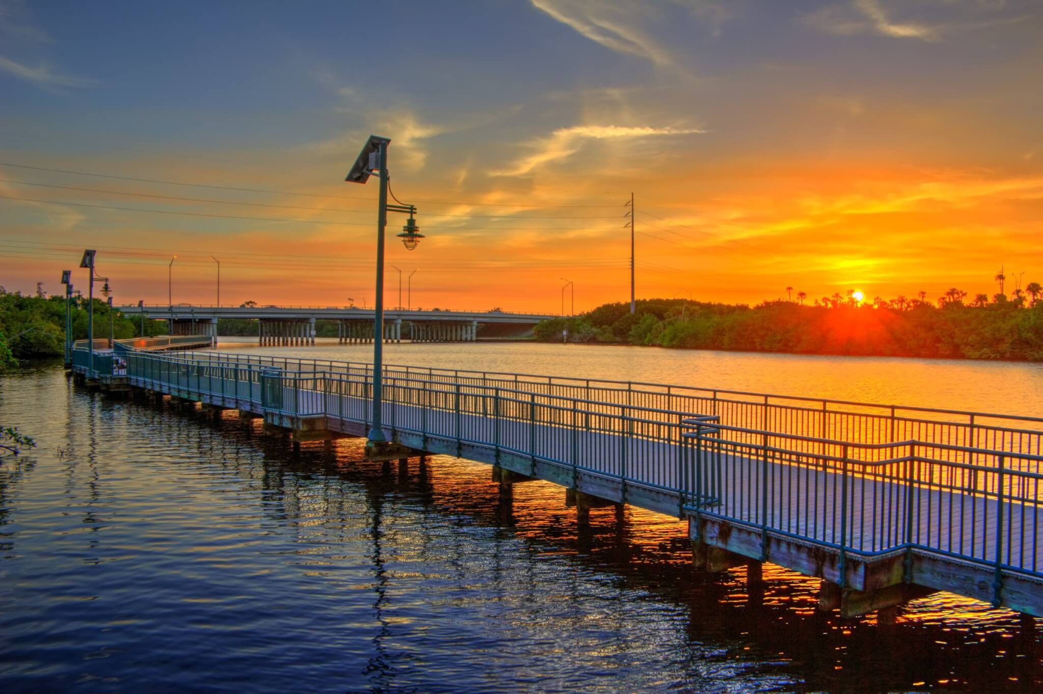 A walking bridge over water with a sunset