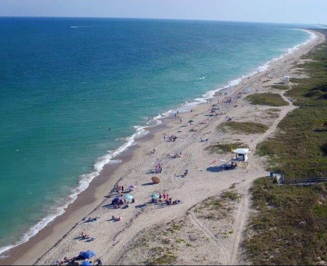 Aerial view of a beach with people using tents and beach umbrellas