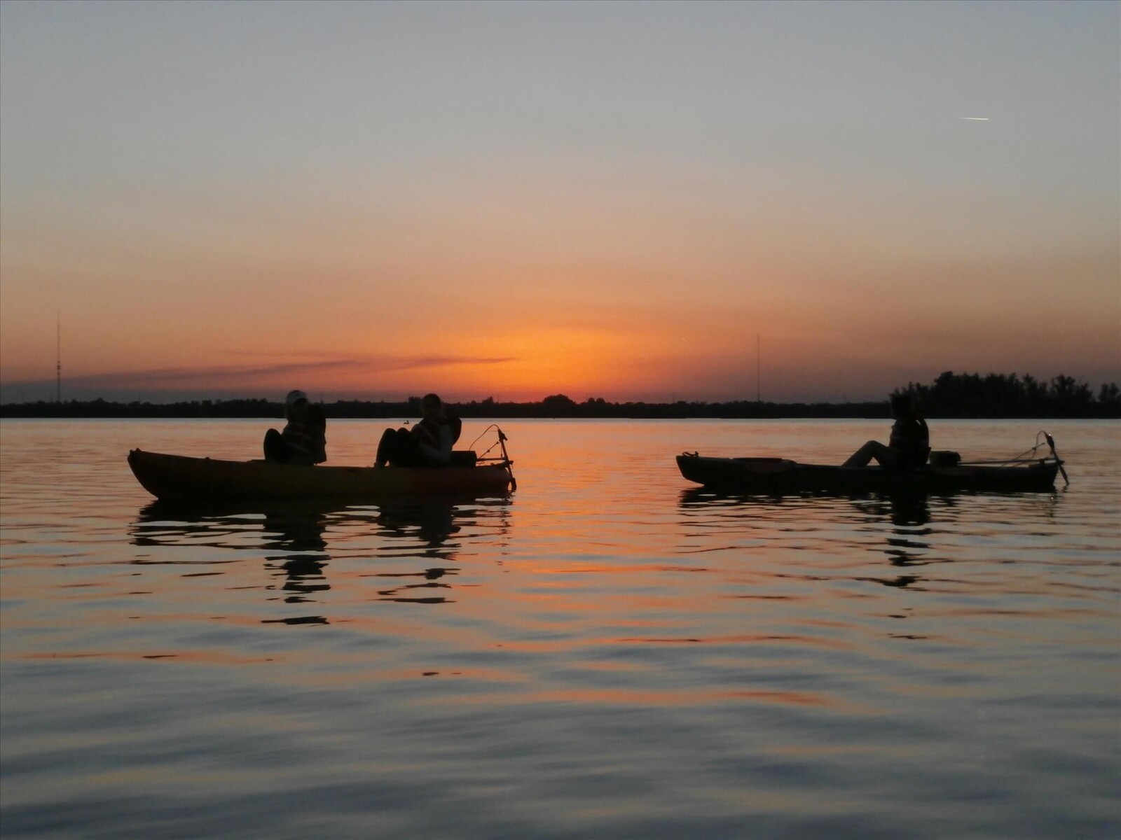 A group of people on boats in the water at dusk