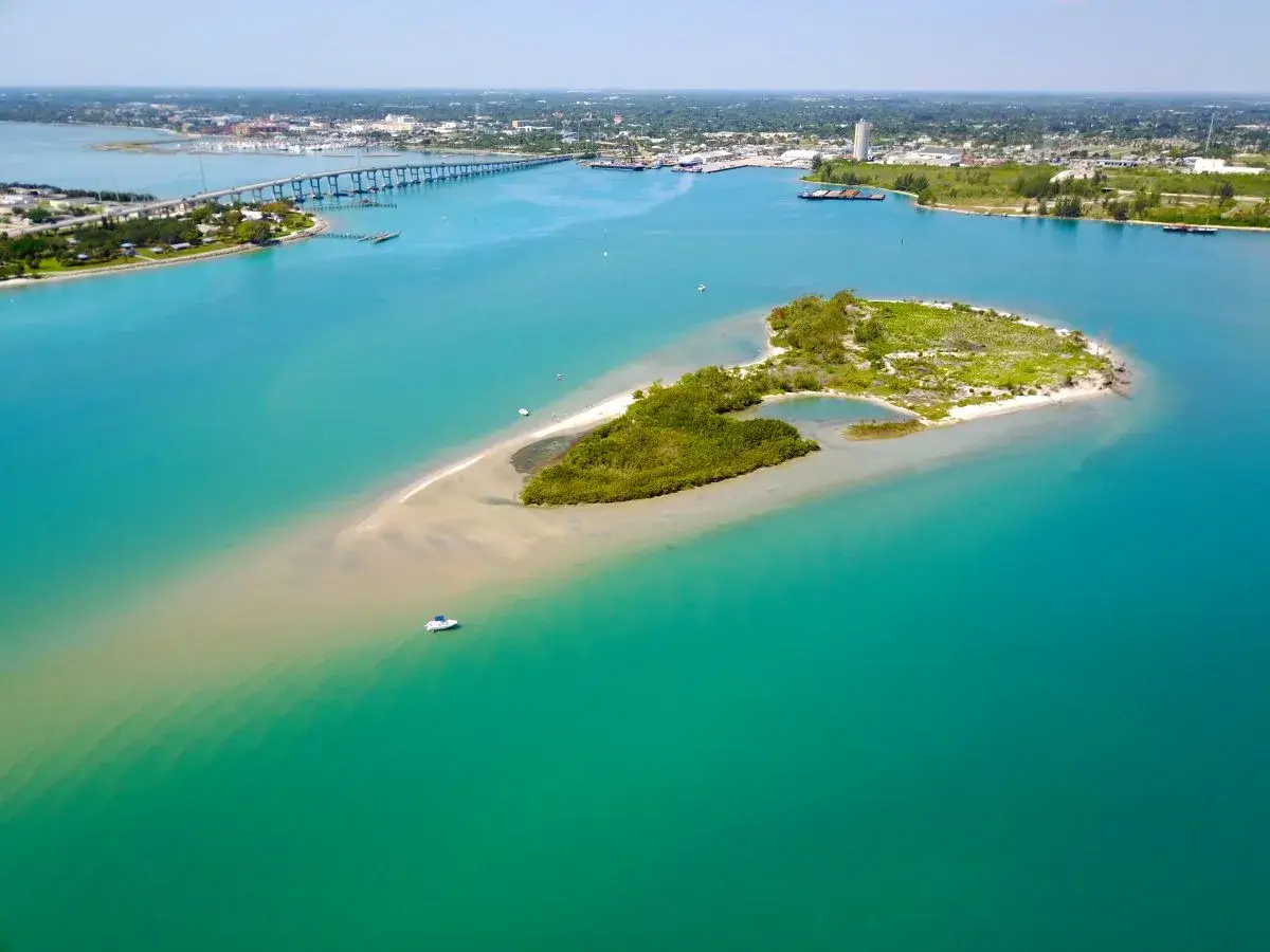 An aerial photo of Wesleys Island surrounded with green and blue hued water in St. Lucie, Florida.