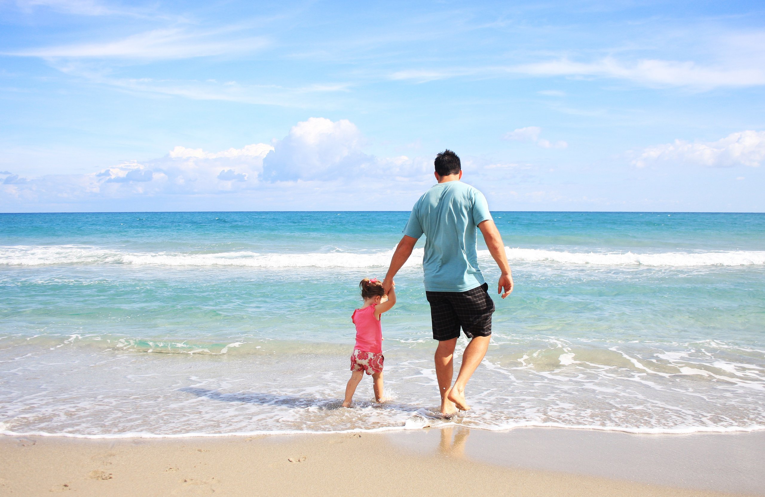 Father holding daughter's hand on the beach in St. Lucie.