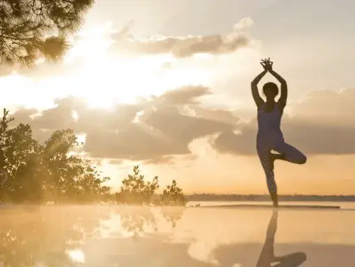 A woman's shadow in front of a bright sunset stands tall in a yoga pose in St. Lucie, Florida. 