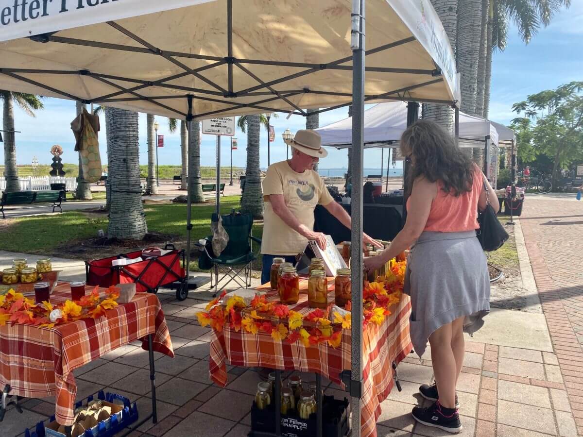 A female patron browses a vendor tent at a farmers market in St. Lucie, Florida. 